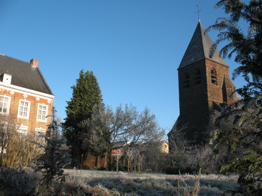 Zicht vanuit de tuin op de pastorie en de kerk